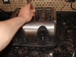 Person Sticking a Fork into a Toaster